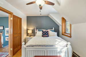Bedroom featuring ceiling fan, light wood finished floors, and baseboard heating