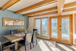 Carpeted dining area featuring french doors and beam ceiling