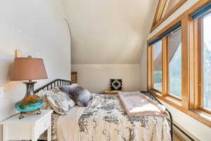 Bedroom with baseboard heating and lofted ceiling