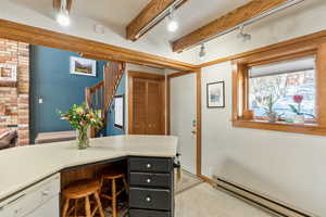Office with light floors, track lighting, a baseboard radiator, baseboards, and beam ceiling