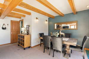 Carpeted dining space with beamed ceiling and baseboards