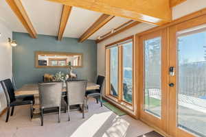 Carpeted dining area with french doors and beamed ceiling