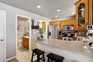Kitchen featuring glass insert cabinets, a sink, appliances with stainless steel finishes, a peninsula, and light tile patterned flooring