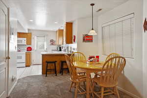 Dining area featuring light tile patterned floors, recessed lighting, light colored carpet, and visible vents