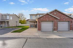 Traditional home featuring an attached garage, driveway, fence, and brick siding