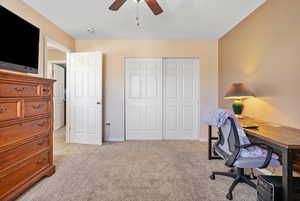Office space featuring light colored carpet, baseboards, and a ceiling fan
