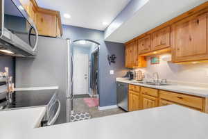 Kitchen with arched walkways, light countertops, a sink, stainless steel appliances, and baseboards