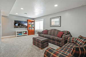 Carpeted living room featuring recessed lighting, baseboards, and a textured ceiling