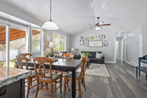 Dining room with visible vents, baseboards, ceiling fan, dark wood-style floors, and lofted ceiling