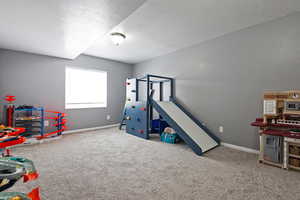 Rec room featuring a textured ceiling, baseboards, and carpet floors