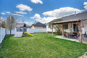 View of yard featuring a patio, a fenced backyard, and a playground