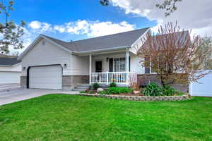 View of front facade with driveway, a porch, an attached garage, and a front lawn
