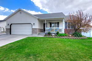 Ranch-style house with a porch, a front lawn, brick siding, an attached garage, and concrete driveway