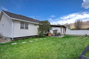 Back of house featuring a patio area, a yard, fence, and a mountain view