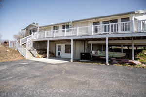 Rear view of property with central AC, covered parking, walk-out from downstairs and stairs up to deck.