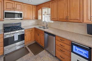 Kitchen with tasteful backsplash, appliances with stainless steel finishes and Corian counters countertops
