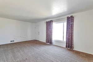 Carpeted empty room with baseboards and visible vents