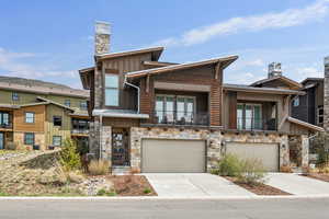 View of front of home featuring an attached garage, driveway, and stone siding