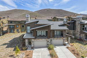 View of front of property with concrete driveway, a mountain view, stone siding, board and batten siding, and an attached garage