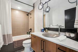 Bathroom with tile patterned flooring, shower / bathtub combination with curtain, vanity, and toilet