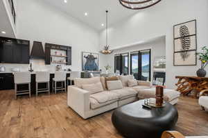 Living room featuring light wood-style floors, high vaulted ceiling, and an inviting chandelier