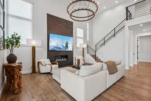 Living area featuring recessed lighting, a tiled fireplace, stairway, a high ceiling, and wood finished floors