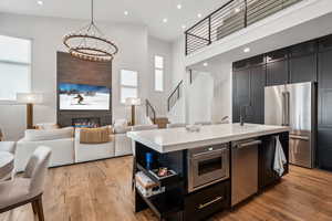 Kitchen with stainless steel appliances, light wood finished floors, light countertops, and an inviting chandelier