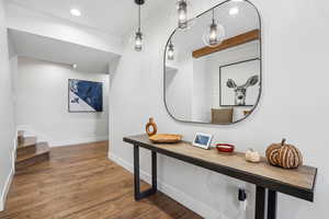 Corridor with wood finished floors, baseboards, stairs, and recessed lighting