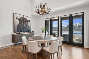 Dining space with a water view, wood-type flooring, baseboards, and an inviting chandelier