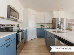 Kitchen with light countertops, white cabinets, light wood-style floors, appliances with stainless steel finishes, and blue cabinets