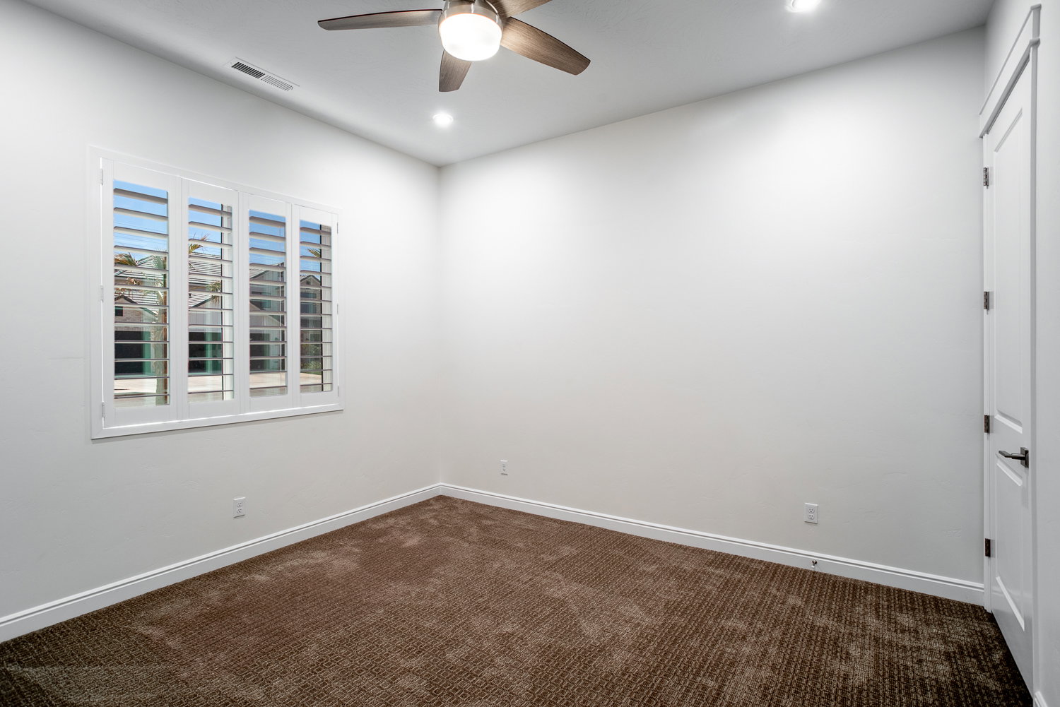 Empty room featuring ceiling fan, dark carpet, visible vents, recessed lighting, and baseboards