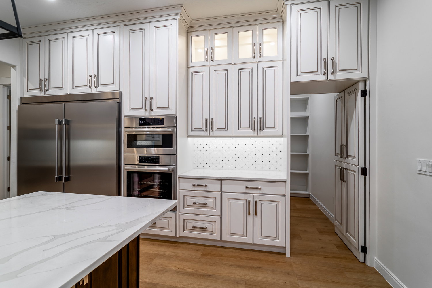 Kitchen with white cabinets, light stone countertops, light wood-style floors, and appliances with stainless steel finishes