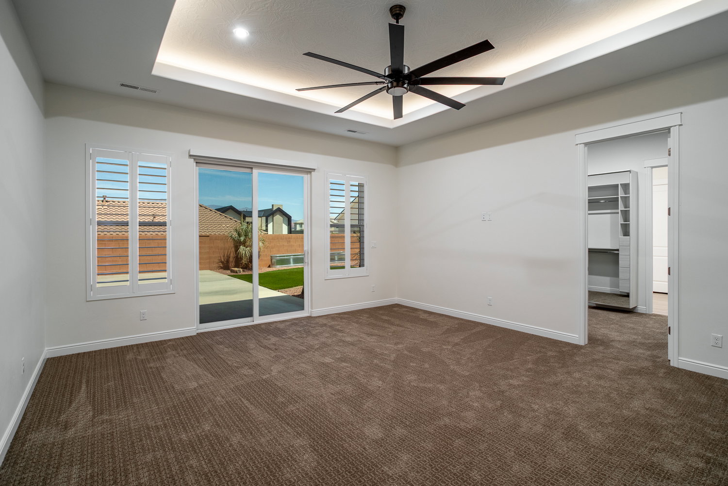 Carpeted spare room featuring visible vents, baseboards, a ceiling fan, and a raised ceiling