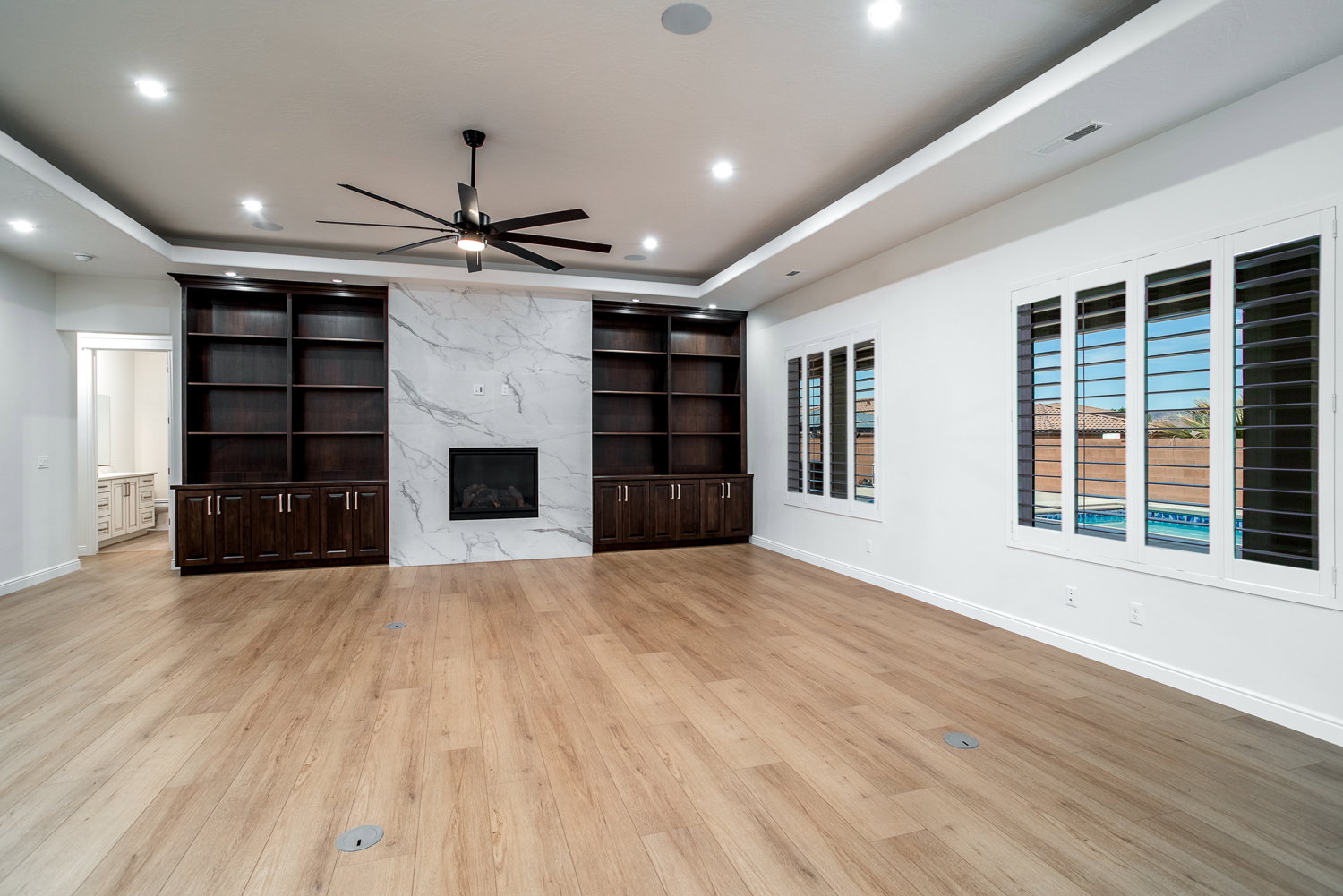 Unfurnished living room with visible vents, baseboards, ceiling fan, a high end fireplace, and wood finished floors