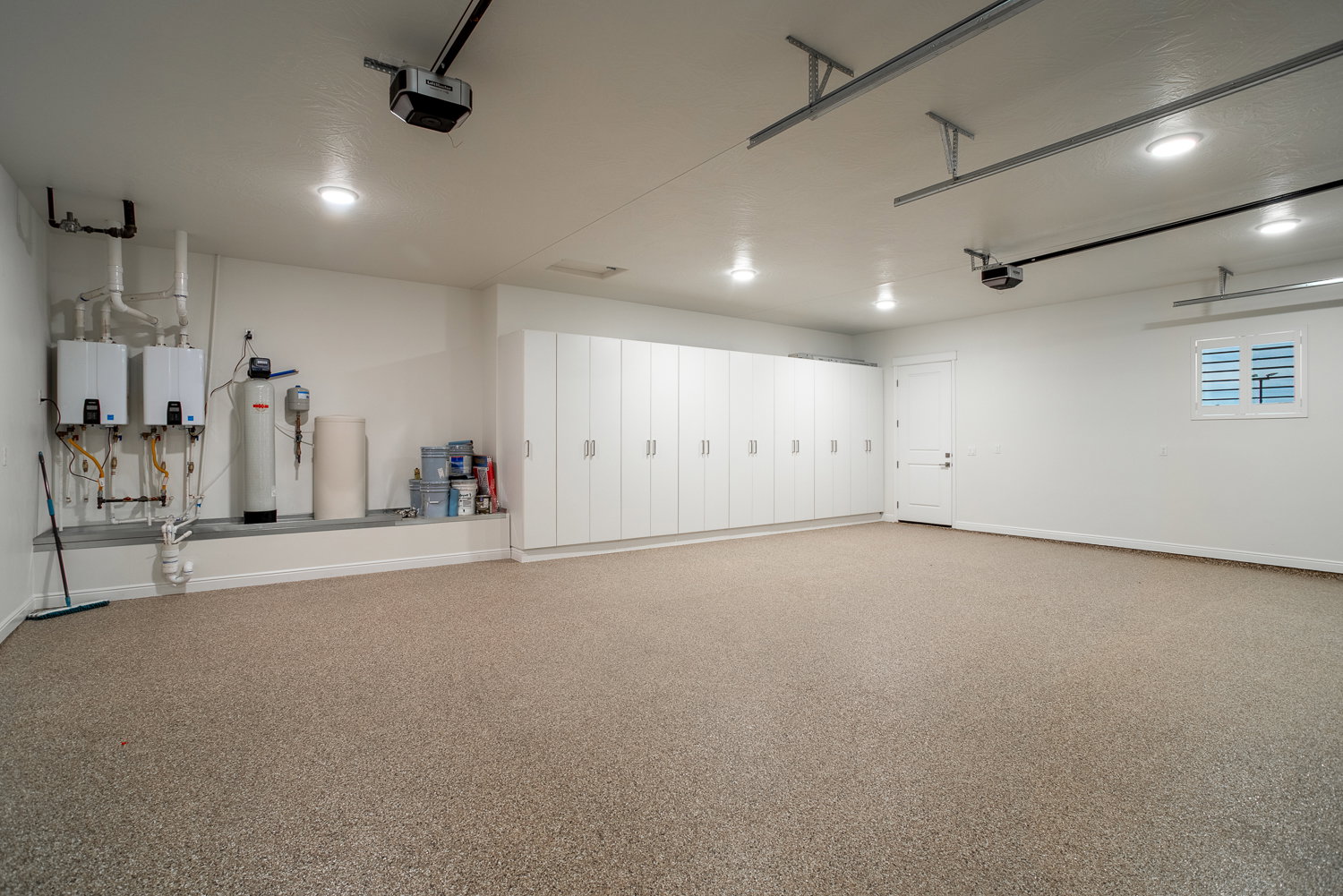 Garage featuring water heater, baseboards, and a garage door opener