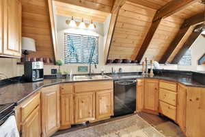 Kitchen featuring light brown cabinetry, wood ceiling, a sink, and black dishwasher