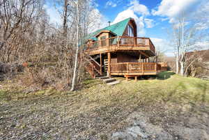 Front of property with decks, a gambrel roof, a lawn, and stairs