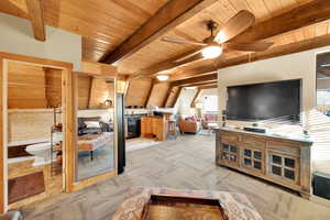 Living area with beam ceiling, light carpet, and wood ceiling