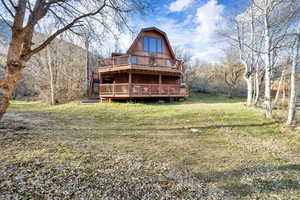 Front of  property featuring two decks, a gambrel roof, and a lawn