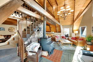Living room featuring a wood stove, an inviting chandelier, wooden ceiling, vaulted ceiling with beams, and stairs