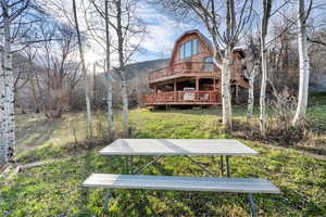 Exterior space featuring a wooden deck, a gambrel roof, and a lawn