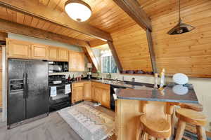 Kitchen featuring black appliances, wooden ceiling, a sink, dark countertops, and light brown cabinets