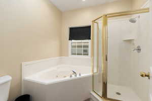 Full bathroom with a whirlpool tub, toilet, and a stall shower