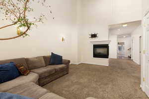 Living room with carpet flooring, baseboards, a multi sided fireplace, and stairway