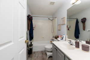 Full bath featuring shower / washtub combination, vanity, visible vents, toilet, and wood finished floors
