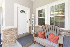 Doorway to property featuring brick siding, stone siding, and stucco siding