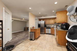 Kitchen with light stone countertops, recessed lighting, visible vents, and stainless steel appliances