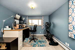 Office with a baseboard radiator, wood finished floors, baseboards, and a textured ceiling