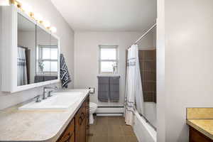 Full bathroom with shower / tub combo, vanity, a baseboard heating unit, tile patterned flooring, and toilet