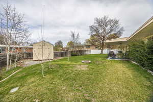 View of yard with a shed, a fenced backyard, an outdoor structure, a patio, and a fire pit